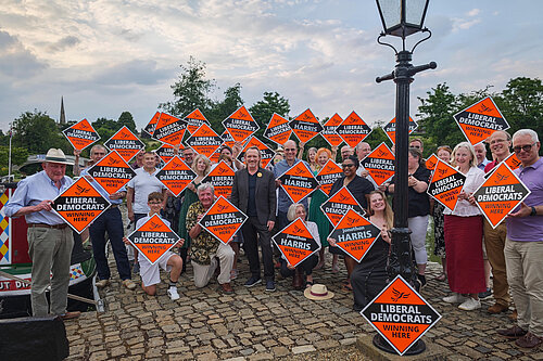 A photo of a large group of people holding up orange "Winning Here" signs