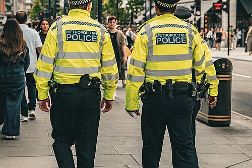 Two Met Police Officers walking along a pavement