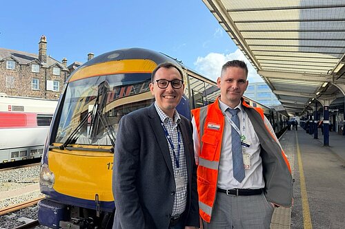 Tom Gordon MP stood in front of a train with a member of staff from Northern Rail