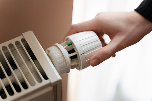 Person adjusting a radiator thermostat 