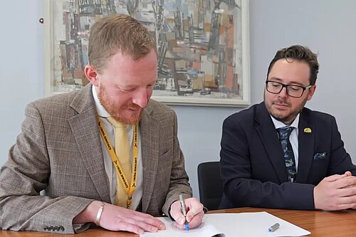 Councillors Colin Ferguson and Nick Hartley signing co-operation agreement