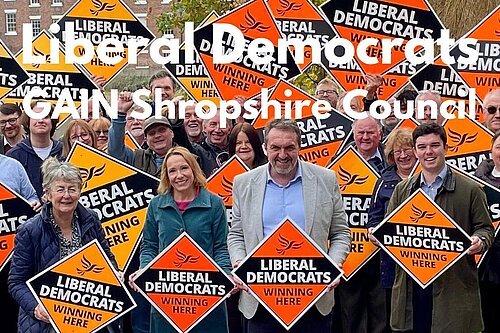 A group of Shropshire Lib Dems with signs stating "Liberal Democrats winning here"