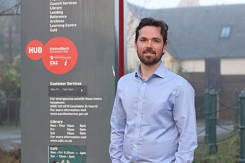 Adam Harley standing next to sign reading details for Kirkintillock Community Hub 