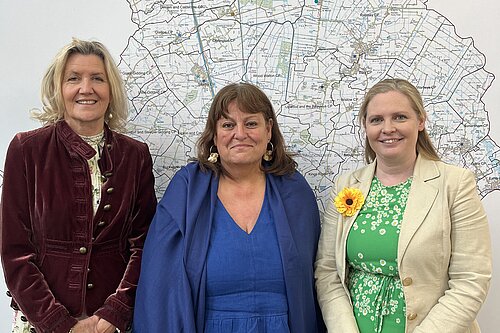 Cllr Sarah Conboy, Cllr Julie Kerr, and Cllr Lara Davenport-Ray stood in front of a map of Huntingdonshire