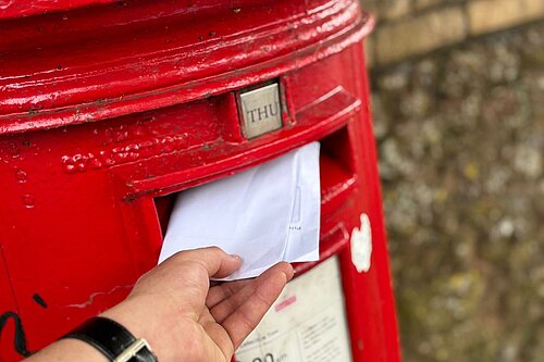 A photo of a letter being put into a letterbox