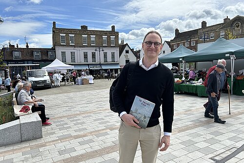 Ian in St Neots Market Square with the market going on behind him