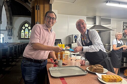 Tom Gordon with Harrogate Homeless Project CEO Richard Cooper at St Peter's Church in Harrogate, being passed a slice of cheescake