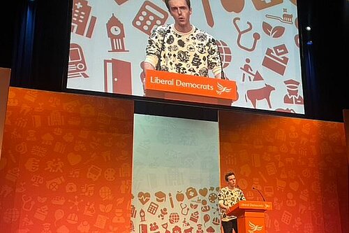 Cllr Nathan Hunt speaking on a Liberal Democrat branded stage