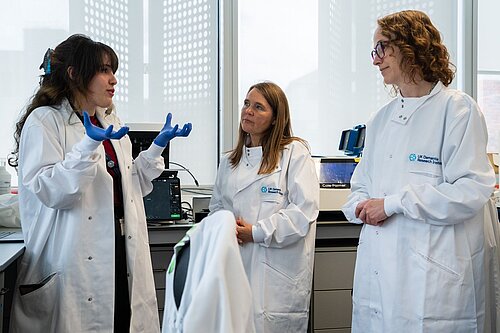 Alison Visiting King’s College London’s dementia research laboratory last week pictured with two scientists in white lab coats, one gesticulating while talking to Alison