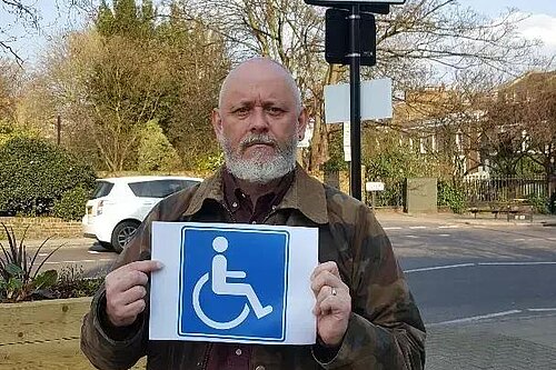 Terry Stacy holding blue badge sign
