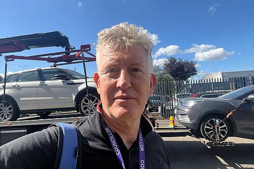 Cllr Jon Oxley taking a selfie next to a towed car.
